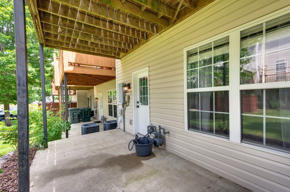 Side view of a house with a wooden deck and utility units.