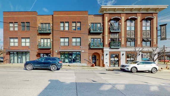 Front view of a three-story brick building with balconies.
