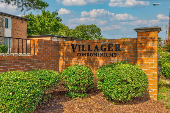 Front view of condominium entrance with brick wall and signage.