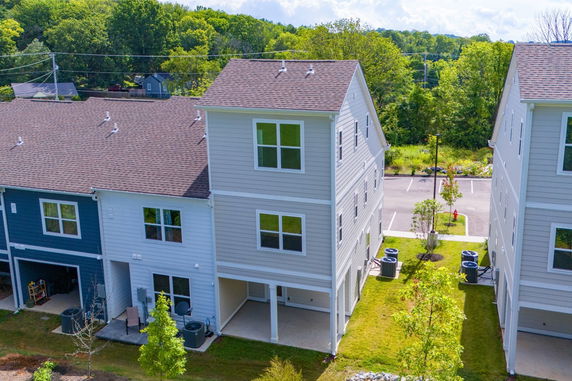 Front view of a three-story townhouse with gray siding and multiple windows.