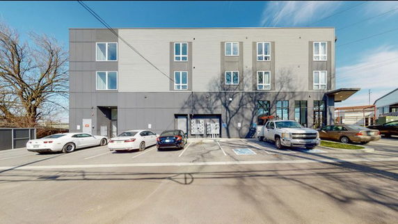 Front view of a three-story building with parking area in front.