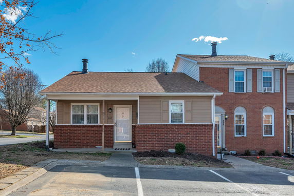 Front view of a single-story house with a chimney and a brick facade.