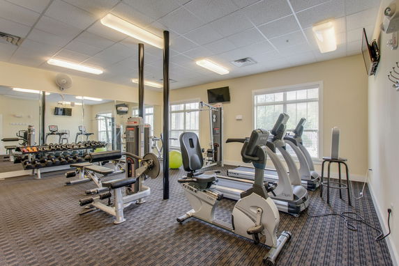 Fitness room with exercise equipment, including treadmills, exercise bikes, and weight machines.