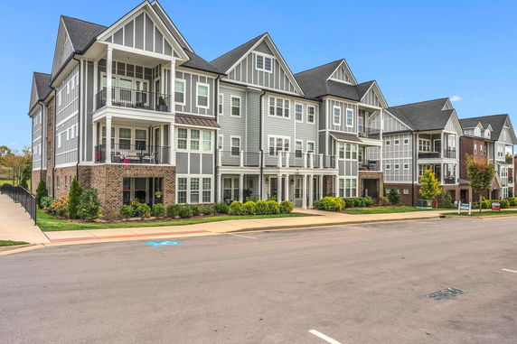 Front view of a multi-story residential building with balconies and gable roofs.