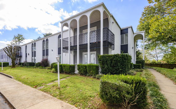 Front view of a two-story building with a balcony and arched design elements.