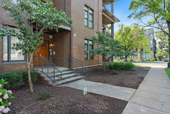 Front view of a multi-story brick building with stairs leading to the entrance.