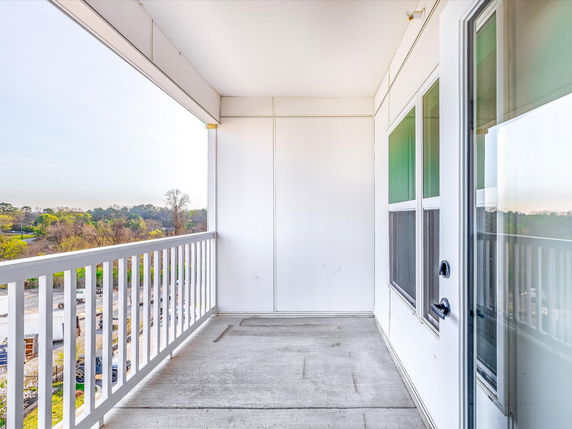 Outdoor balcony with view of surrounding greenery and buildings.