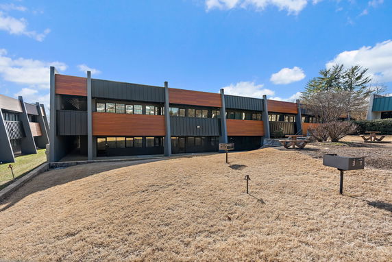 Front view of a modern two-story building with extensive use of wood and dark cladding.