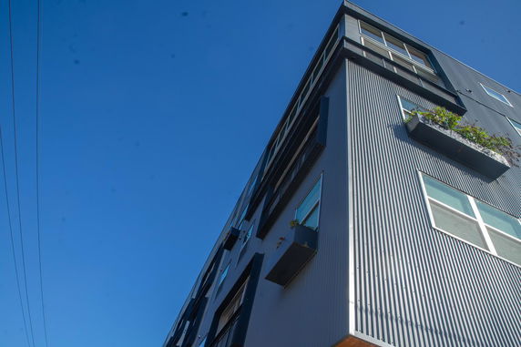 Angled view of a modern multi-story building with metal siding and multiple windows.