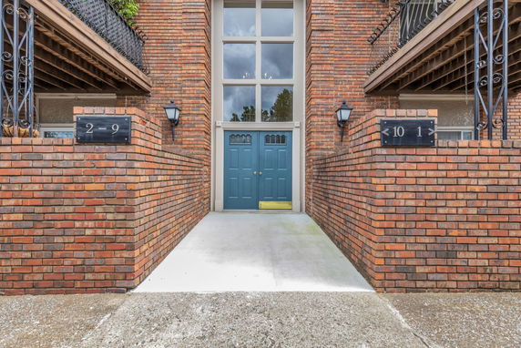 Front view of a brick building with blue double doors and large windows.