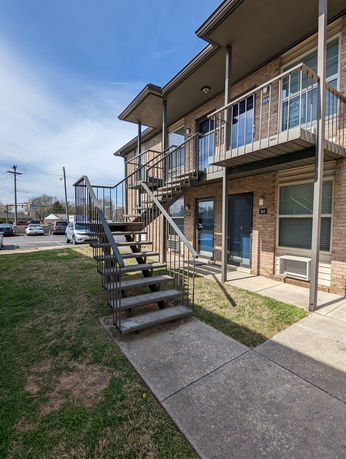 Front view of a two-story apartment building with external staircase.