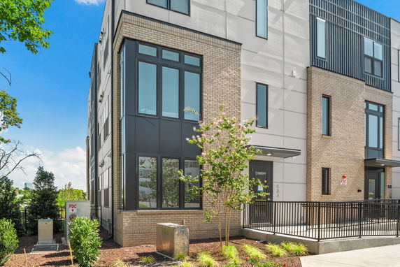 Front view of a modern multi-story building with large windows and brick facade.