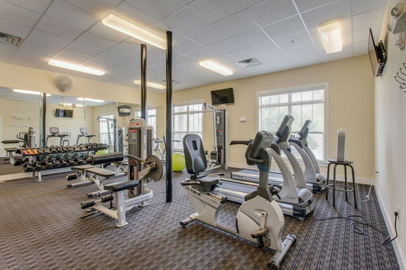 Interior view of a gym with exercise equipment and mirrors.