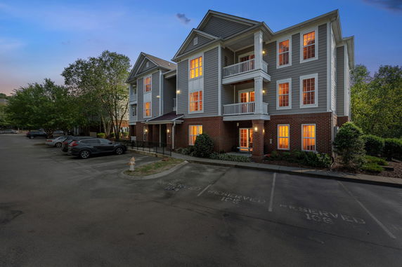 Front view of a multi-story residential building with balconies and lit windows.