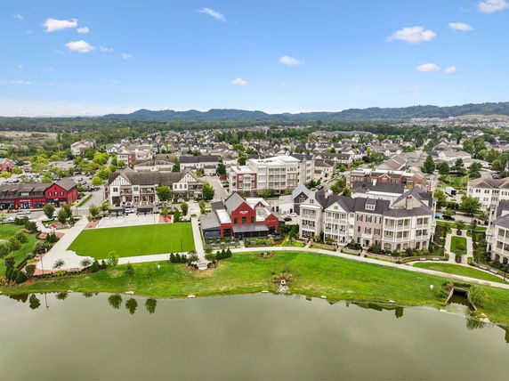 Panoramic view of a neighborhood with multiple residential buildings and a pond in the foreground.