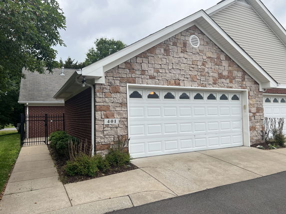 Front view of a house with a stone facade and white double garage door.