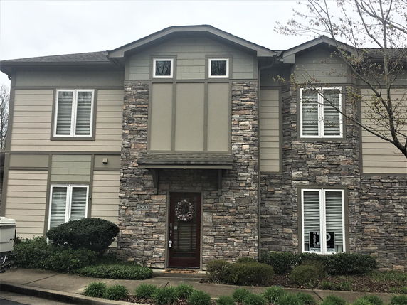 Front view of a two-story house with stone and siding exterior.