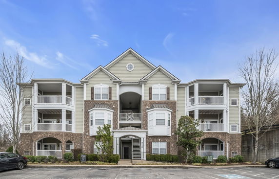 Front view of a multi-story residential building with balconies and brick facade.