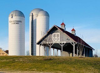 Farm building with a red roof and two silos.