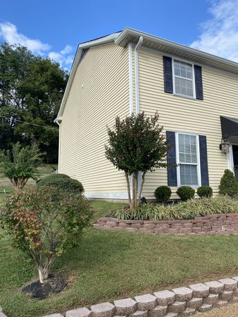 Side view of a two-story house with yellow siding and white trim.