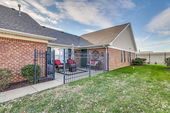 Front view of a brick single-story house with a fenced patio area.