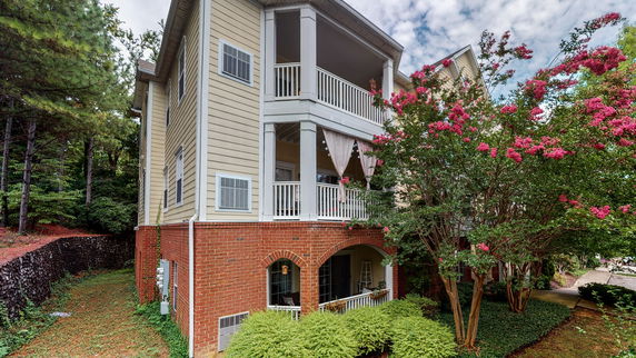 Side view of a multi-story house with brick and siding exterior.
