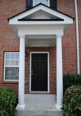 Front view of a building with a black door and white columns.