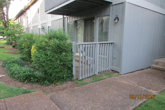 Front view of a multi-story building with a small balcony and sliding glass doors.