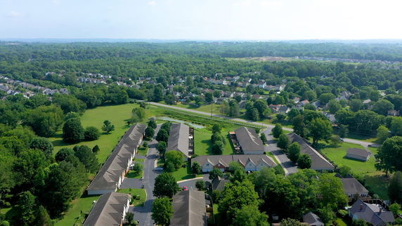 Aerial panoramic view of a residential area with numerous houses surrounded by green trees.