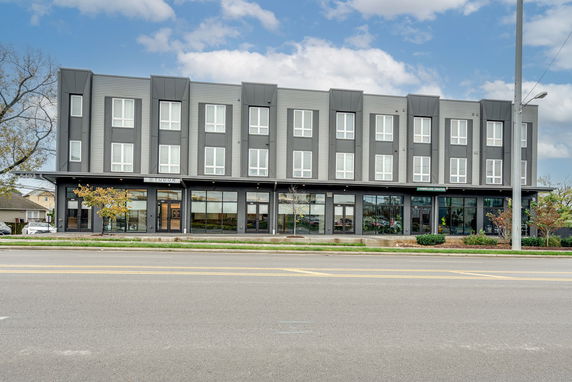 Front view of a modern three-story commercial building with large windows and a grey facade.
