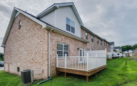 Side view of a two-story brick townhouse with a small deck.