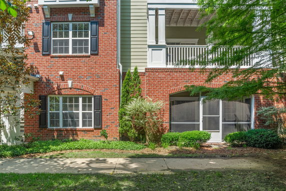 Front view of a building with a mix of brick and siding, featuring windows with black shutters.