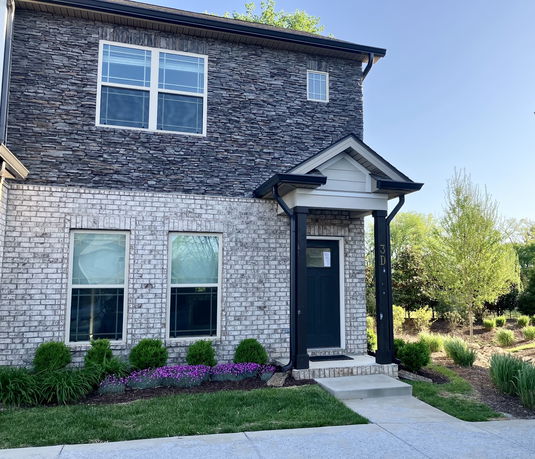 Front view of a two-story house with brick and stone exterior and a small porch.