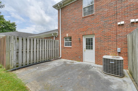 Side view of a brick house with a white door and a wooden fence.