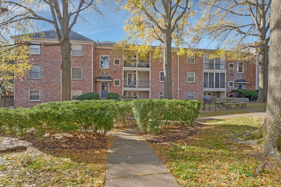 Front view of a three-story brick apartment building with balconies.