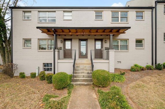 Front view of a two-story building with a small porch and steps leading up to the entrance.