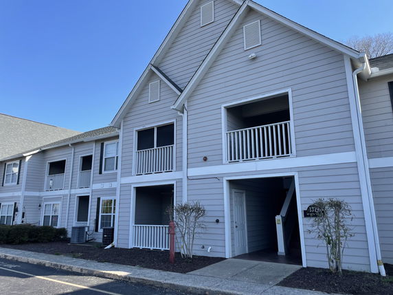 Front view of a two-story residential building with balconies and a central entrance.