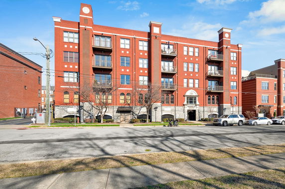 Front view of a multi-story building with red brick facade and balconies.