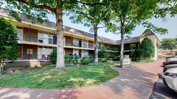 Front view of a two-story apartment building with a sign that reads 'Lancaster'.