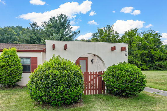Front view of a single-story house with an arched entryway and red accents.