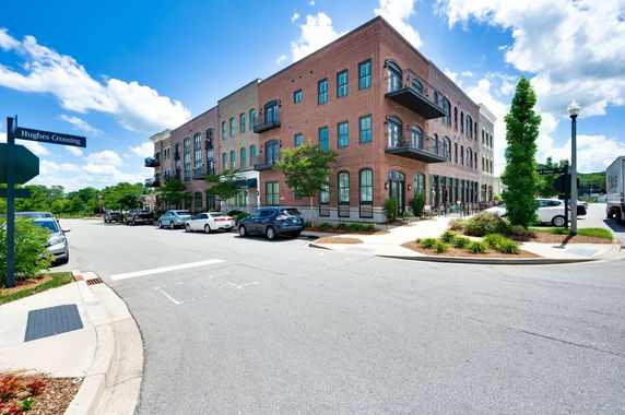 Front view of a three-story brick building with balconies and large windows.
