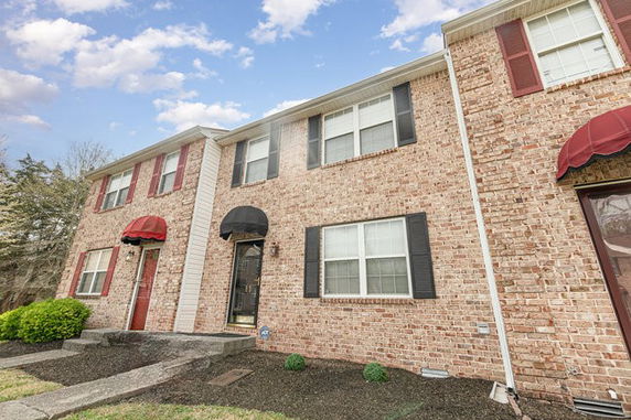 Front view of a two-story brick townhouse with multiple windows and red accents.