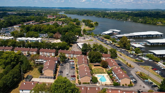 Panoramic view of residential buildings near a river with parking areas and a swimming pool.