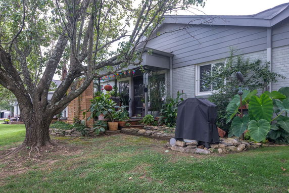 Front view of a house with a covered porch and surrounding plants.