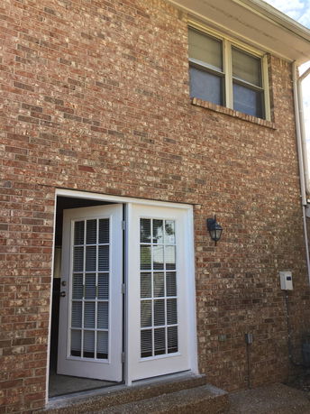 Front view of a brick house with a double door and a window above.