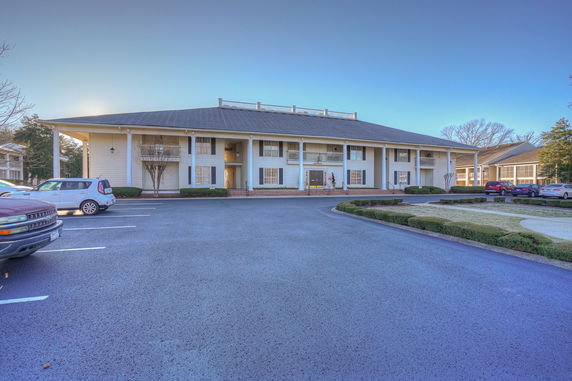 Front view of a long two-story building with a large parking area.