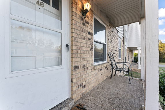 Front view of a brick house entrance with a chair on the porch.