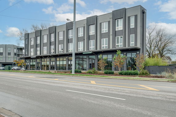 Front view of a modern three-story building with large windows and storefronts on the ground floor.