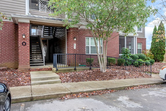 Front view of a brick residential building with stairs leading to upper floors.