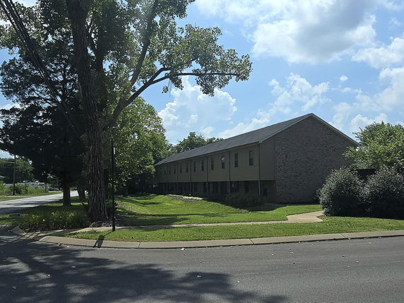 Side view of a two-story building with a brick wall.